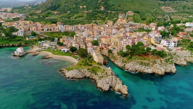 Aerial forwarding shot of amazing landscape of Sicily along the beautiful coastal town of Caletta Sant'Elia, Santa Flavia PA, Italy on a cloudy day.