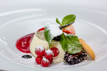 Close up. Flying powdered sugar. Panakota with raspberries and mint. Vertical shot. Summer dessert. Light background