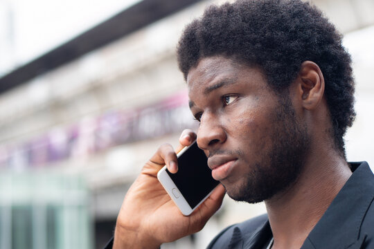 Serious African business man talking, negotiating via smartphone