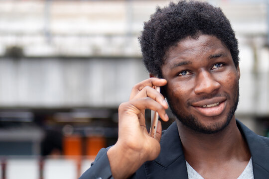 Happy smiling African business man talking, negotiating via smartphone