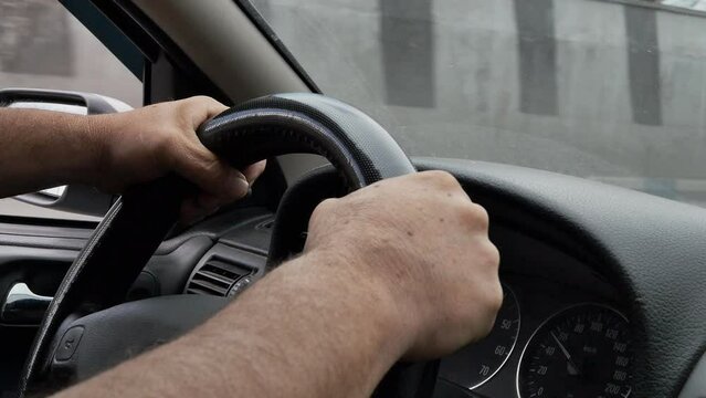 the driver's hands firmly grip the steering wheel when driving on a busy city highway. slow motion