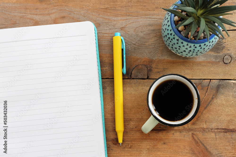 Poster top view image of open notebook with blank pages and cup of coffee over wooden desk. ready for addin
