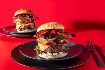 Bold fresh cheeseburger loaded with lettuce, cucumber, tomato and bacon on vibrant red