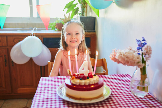 Happy little girl celebrating her fourth birthday and making a wish