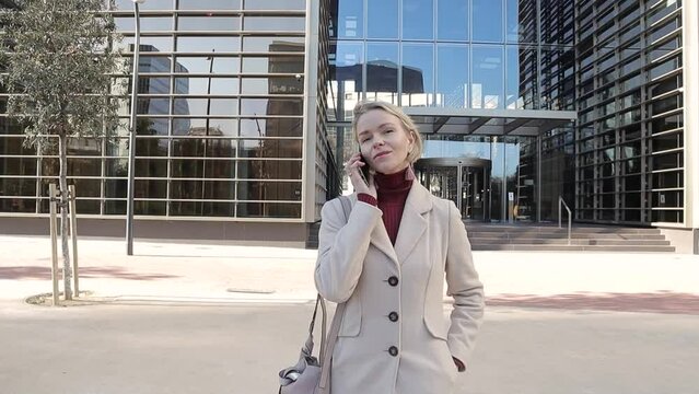 Professional businesswoman talking on the phone while walking on the street after leaving the office.