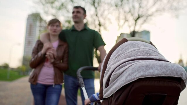 Young family walking with a pram near the lake