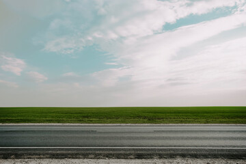 Asphalt Outdoor Road Among the Green Meadow Field. Side View. Straight Horizon Line. Blue Sky on...