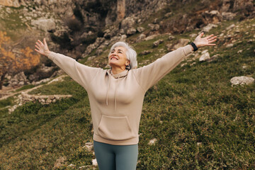 Happy senior woman celebrating while hiking in the hills