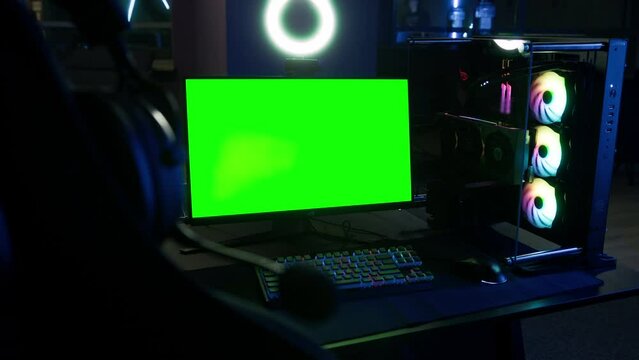 Shot of a gaming station. Computer green screen with copy space, colorful keyboard, mouse and PC. Glowing coolers with LED lights. High quality 4k footage