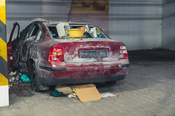 photo of a destroyed car with trash in the underground parking lot full shot . High quality photo