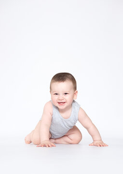 eight month old baby boy crowling on the ground and looking at camera