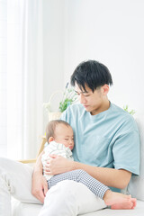 Fototapeta na wymiar 赤ちゃんを抱く父親　リビング