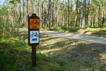 Szlak rowerowy ścieżką leśną. Oznakowanie trasy rowerowej. Mała głębia ostrości, bokeh, f/1,4. Zieleń, błękit, wiosna. - obrazy, fototapety, plakaty