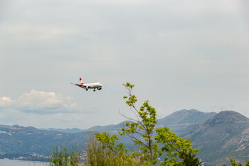 Fototapeta na wymiar Red-white color airplane landing in Dubrovnik airport (Cavtat).