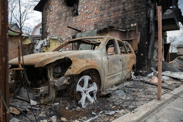 Fototapeta premium War in Ukraine. Ruins of a house and burned car.