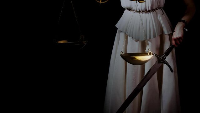 Themis, the goddess of justice blindfolded, with scales and a sword in her hands. A fair trial. Antique goddess, photo on a black background
