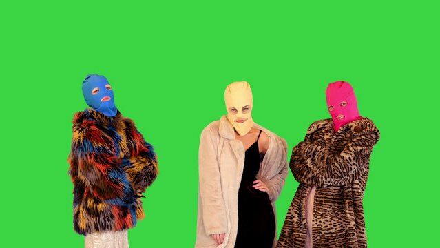 A group of girls in colored balaclavas pose in fashionable manner on a Green Screen, Chroma Key.
