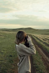 Foto auf Acrylglas Schöne Frau, die bei Sonnenuntergang mit Retro-Fotokamera auf dem Feld spazieren geht © Nikita