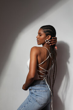 Side view portrait of African young woman with braids posing on grey background.