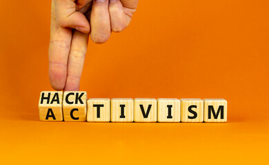 Activism or hacktivism symbol. Businessman turns wooden cubes and changes the word Activism to Hacktivism. Beautiful orange table orange background, copy space. Business activism hacktivism concept.
