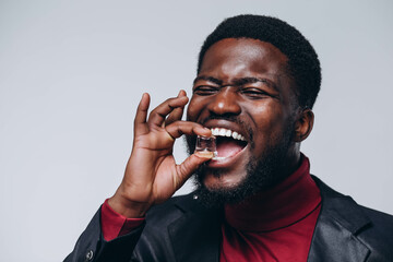 A good-looking adult is presenting holding a ice cube. By showing that he has strong teeth, he can...