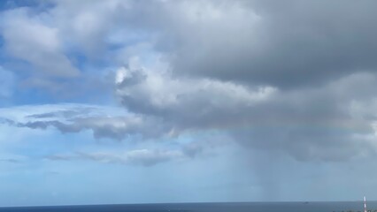 Obraz premium Long rainbow with dramatic clouds over the Ala Moana beach area, Oahu Island, Hawaii year 2022 April