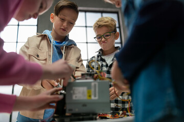 Kids with teacher working together on project with electric toys and robots at robotics classroom.
