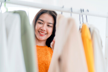 smart beautiful asian female woman enjoy hand choose shopping cloth on hanger at shop store mall,...