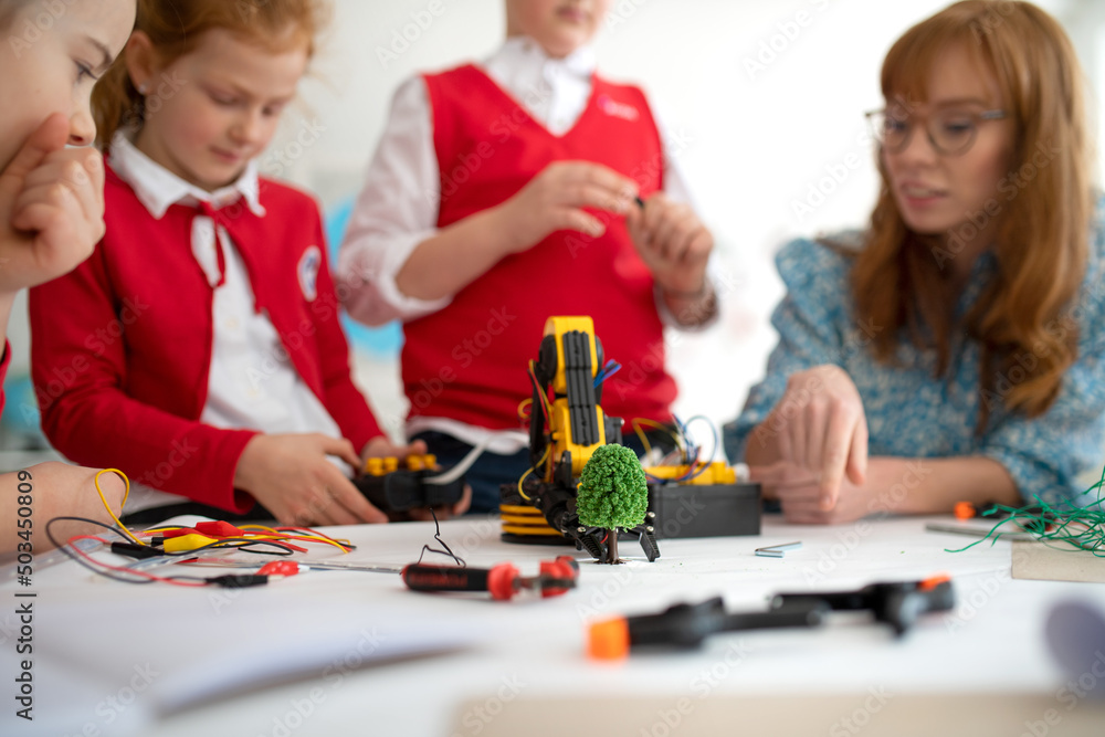 Sticker group of kids with young science teacher programming electric toys and robots at robotics classroom