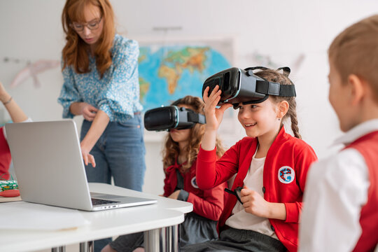 Happy schoolchildren wearing virtual reality goggles at school in computer science class