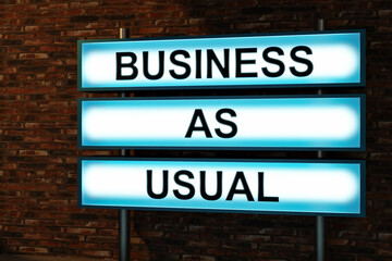 Business as usual. Text in capital letter showed on a light box in front of a red brick wall. Business, routine and inspiration concept. 3D illustration