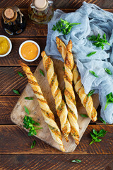 Puff sticks with cheese and herbs. Homemade breadsticks with sauce