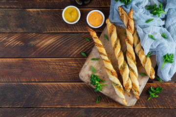 Puff sticks with cheese and herbs. Homemade breadsticks with sauce