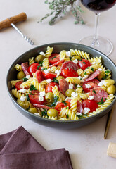 Salad with fusilli pasta, sausage, olives and cottage cheese. Italian food.