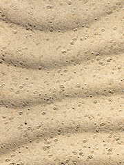 Arena ondulada en dunas salpicada por agua de lluvia