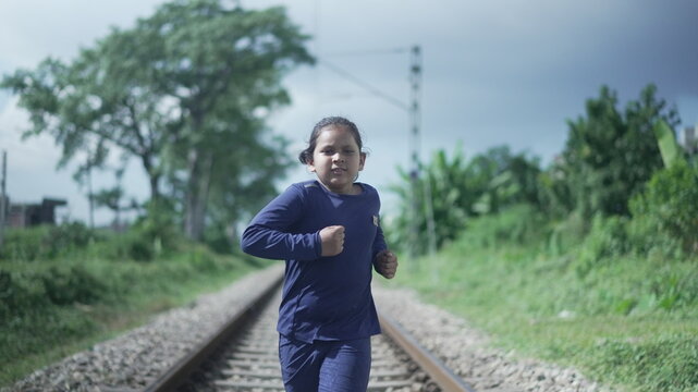Indian Kid running on the railway track in the Himalayan range of India, greenery in the background. Physical fitness training. High-quality photo