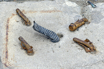 Bent rusty bolts of fastening of a support of street lighting on a spring day