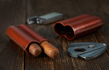View of a leather case with two Cuban cigars, a lighter and a cutter.