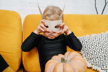 Little girl dressed for halloween sitting on a couch, grimacing, showing claws.
