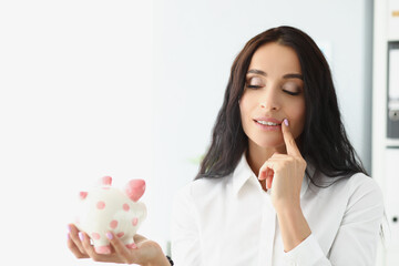 Woman hold piggybank, think of better way to use money, saving up for future