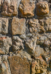 An old ancient wall. The wall is built of raw stones of various shapes. Panorama from several photos.