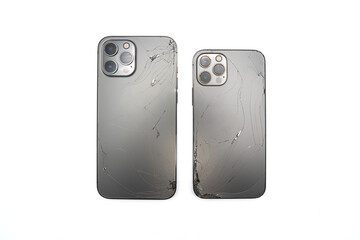 Two space grey modern smartphones has broken back glass on white background.