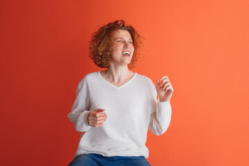 Portrait of happy looking red-haired woman cheerfully posing isolated over red studio background