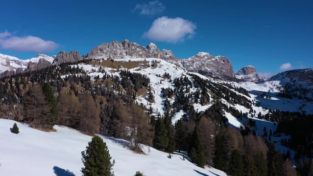 Pizes de Cir Mountain Range and Gardena Pass on Sunny Winter Day. South Tyrol, Dolomites, Italy. Aerial View . Drone Flies Forward over Trees at Low Level