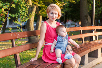 beautiful mother with her daughter and son are sitting on a bench in the park in the summer