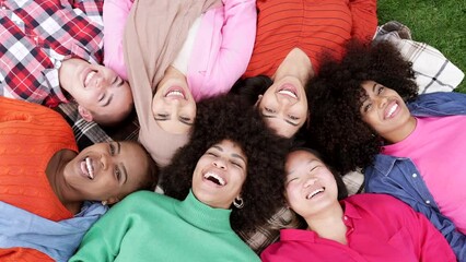 group of multiracial women lying on the grass, happy women smiling happily on a day in the park