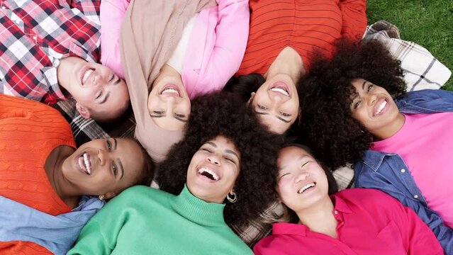 group of multiracial women lying on the grass, happy women smiling happily on a day in the park