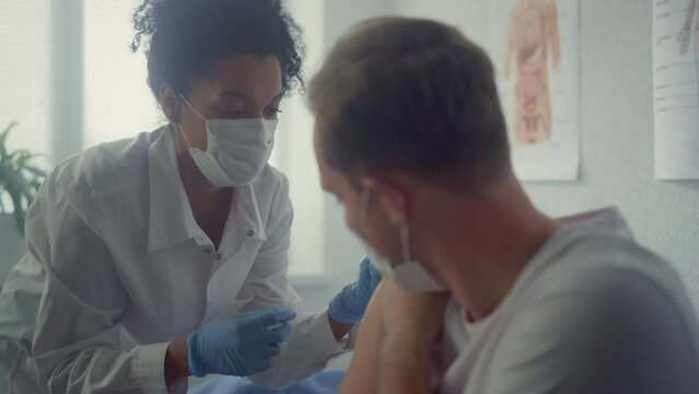 Guy getting covid vaccination in office clinic close up. Doctor making injection