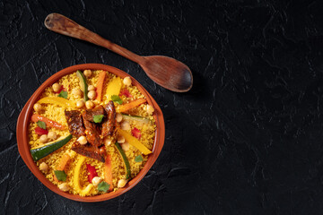Couscous with meat and vegetables, festive Moroccan dinner, overhead shot with a place for text on a black background