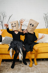 Scary little girls in halloween costumes wearing paper bags with scary faces